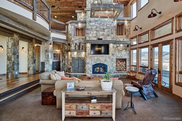 carpeted living room with french doors, a high ceiling, and a stone fireplace