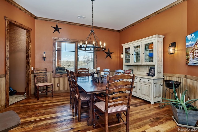 dining area with wood-type flooring, crown molding, and a chandelier