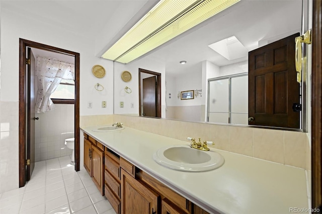17852 E Long Ave, Centennial, CO 80016 - full bathroom with tile patterned flooring, a skylight, tile walls, double vanity, and a stall shower