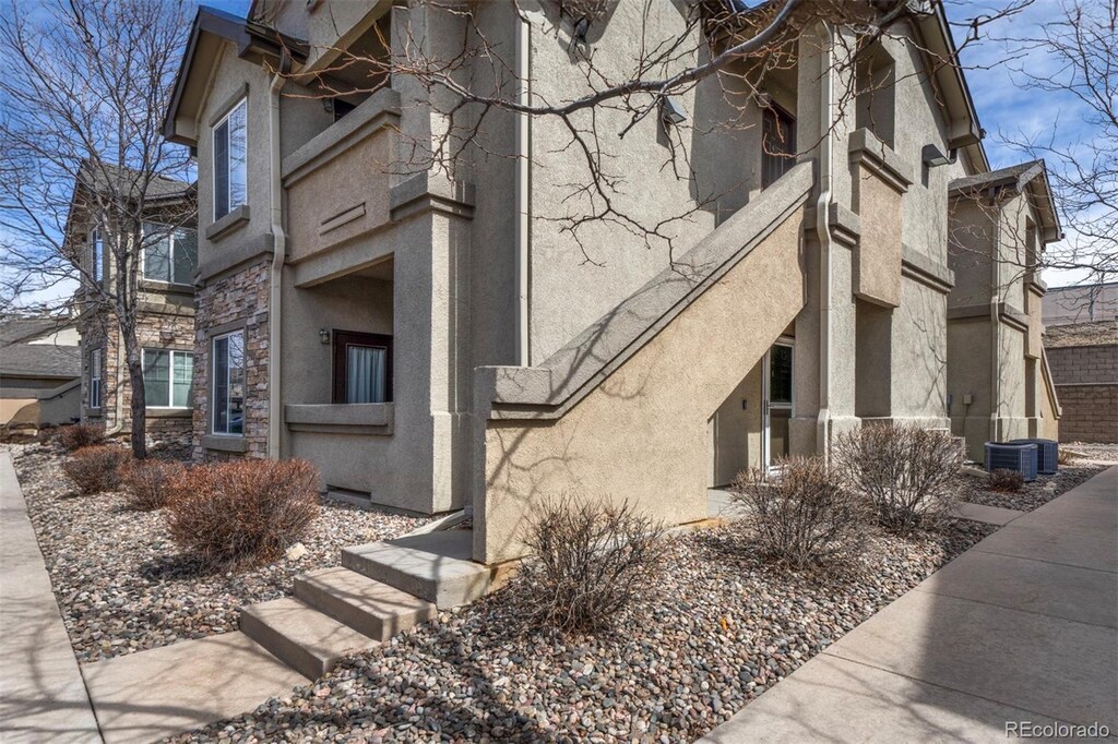7124 Ash Creek Hts Unit 104, Colorado Springs, CO 80922 - view of side of property featuring stone siding, stucco siding, and central air condition unit