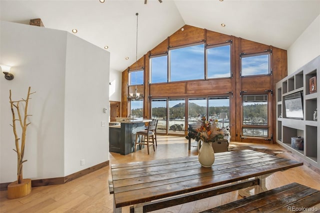 dining area with light wood-type flooring and high vaulted ceiling