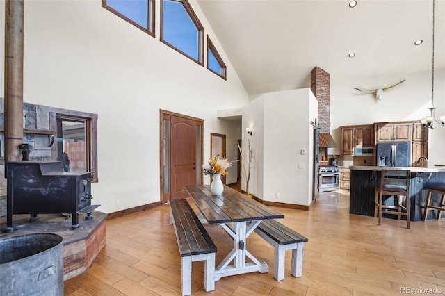 dining space with light hardwood / wood-style floors and high vaulted ceiling