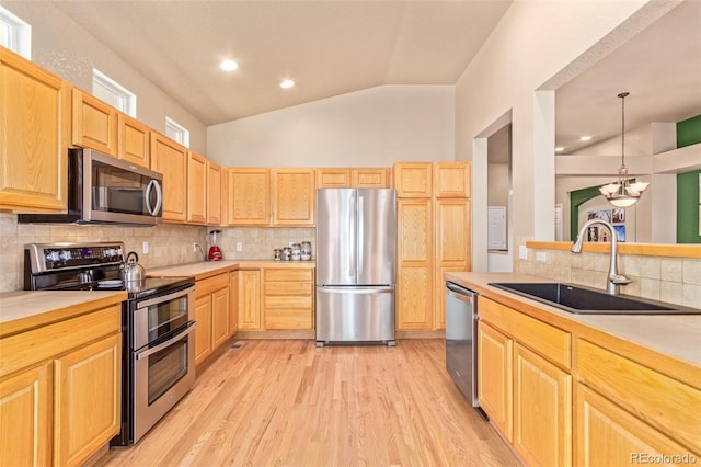 kitchen with pendant lighting, backsplash, sink, appliances with stainless steel finishes, and light hardwood / wood-style floors