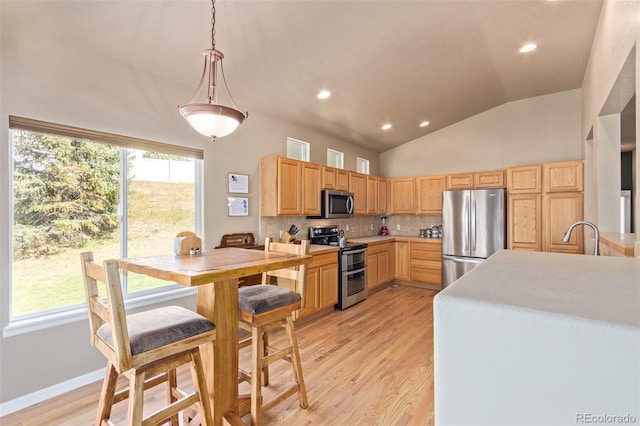 kitchen with light brown cabinets, stainless steel appliances, decorative backsplash, and light hardwood / wood-style floors