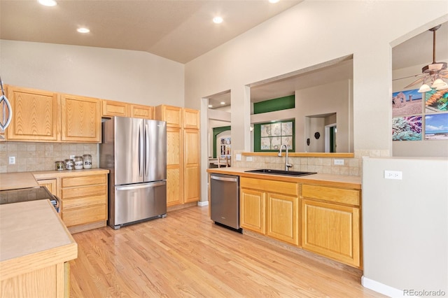 kitchen featuring sink, ceiling fan, decorative backsplash, appliances with stainless steel finishes, and lofted ceiling