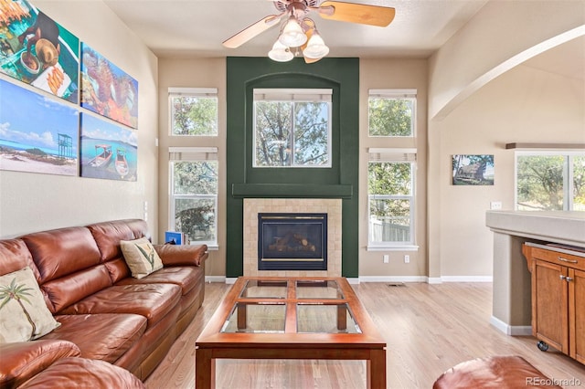 living room featuring light hardwood / wood-style flooring, ceiling fan, and a tile fireplace