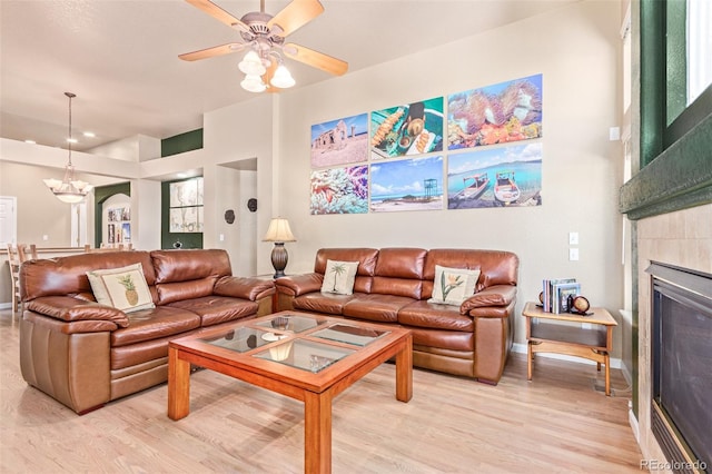 living room with ceiling fan with notable chandelier and light hardwood / wood-style floors