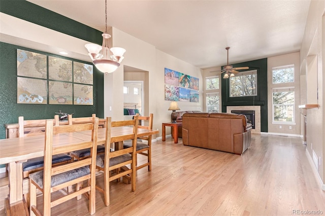 dining space featuring ceiling fan with notable chandelier and light hardwood / wood-style floors