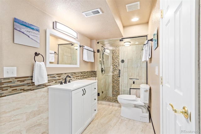 bathroom with an enclosed shower, toilet, tile walls, vanity, and a textured ceiling