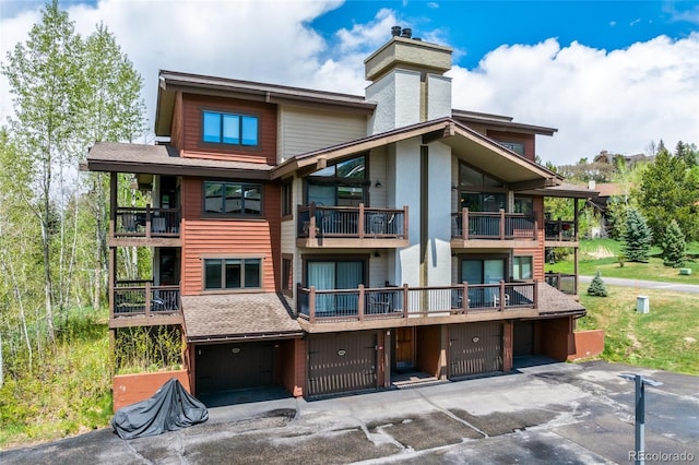 1655 Ranch Rd Unit 403, Steamboat Springs, CO 80487 - back of property featuring a chimney, a garage, a balcony, and driveway