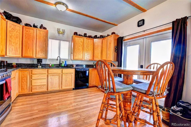 kitchen featuring light wood-type flooring, dishwasher, sink, stainless steel stove, and vaulted ceiling