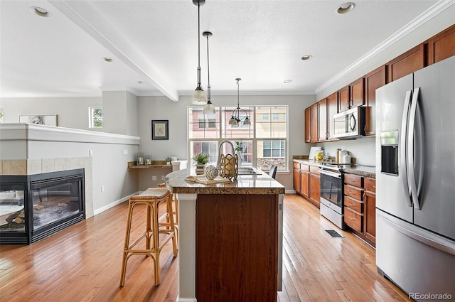 13524 Via Varra, Broomfield, CO 80020 - kitchen featuring stainless steel appliances, light wood-style floors, ornamental molding, a breakfast bar, and an island with sink