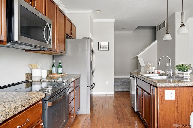 13524 Via Varra, Broomfield, CO 80020 - kitchen with stainless steel appliances, crown molding, hardwood / wood-style flooring, brown cabinetry, and baseboards