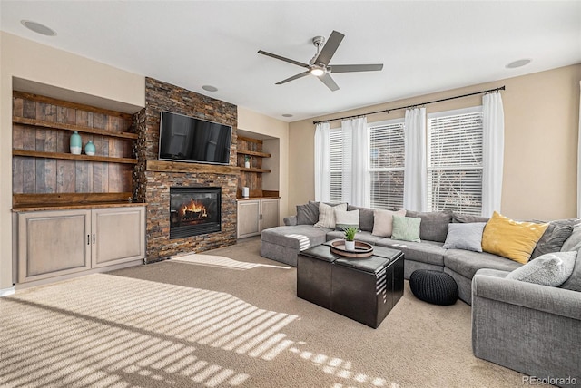 carpeted living room featuring a fireplace, ceiling fan, and built in features