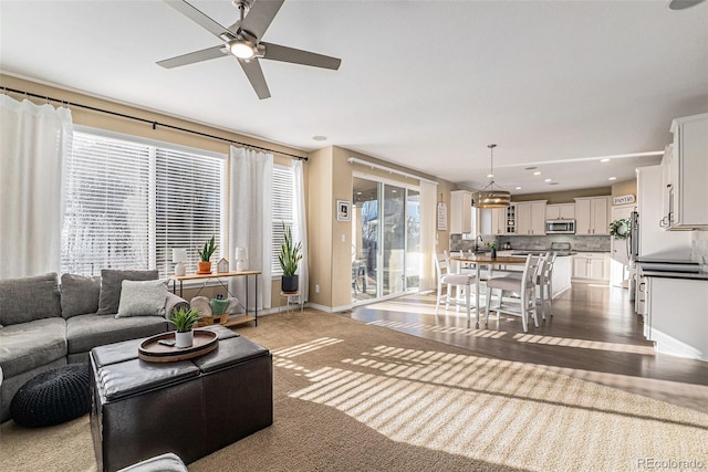 living room featuring ceiling fan, a healthy amount of sunlight, sink, and light carpet