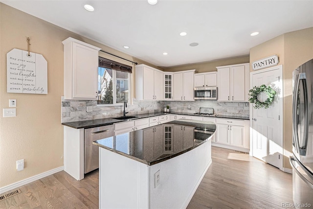 kitchen featuring a center island, sink, light wood-type flooring, white cabinetry, and stainless steel appliances