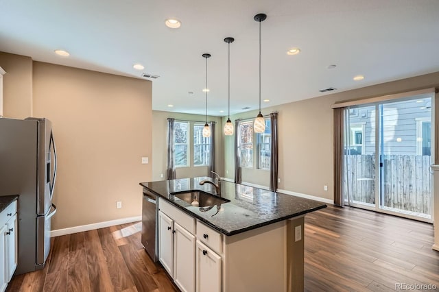 kitchen featuring a center island with sink, sink, dark stone countertops, white cabinetry, and stainless steel appliances