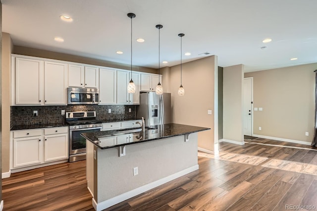 kitchen with stainless steel appliances, white cabinetry, a center island with sink, and sink