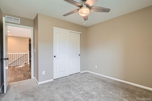 unfurnished bedroom with ceiling fan, light colored carpet, and a closet