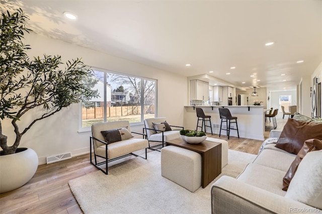 living room featuring light wood-style flooring, visible vents, baseboards, and recessed lighting