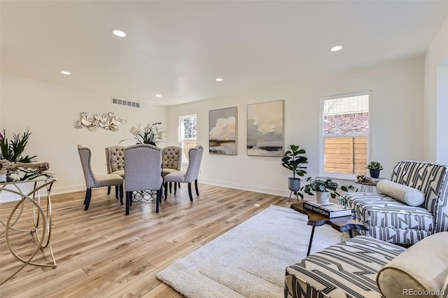 living room featuring light wood-type flooring, baseboards, visible vents, and recessed lighting