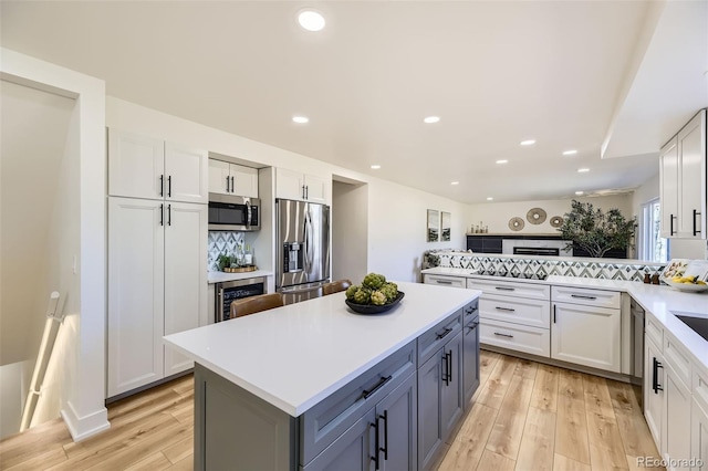 kitchen featuring stainless steel appliances, light countertops, light wood finished floors, and tasteful backsplash