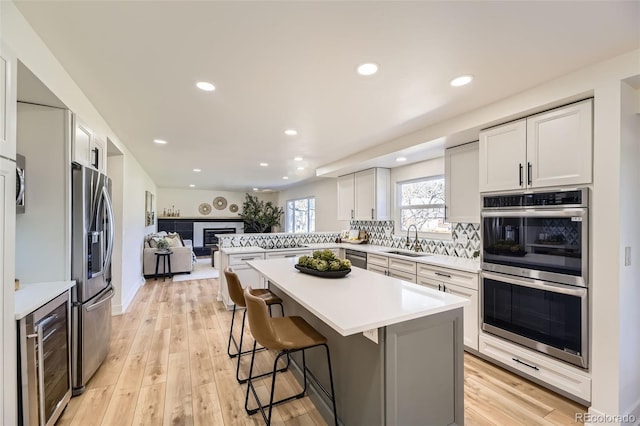 kitchen with a peninsula, stainless steel appliances, a sink, and light countertops