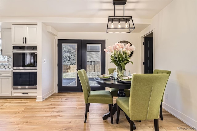 dining area with baseboards, french doors, and light wood-style floors