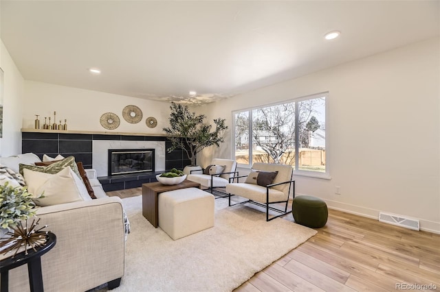 living area with a fireplace, recessed lighting, visible vents, wood finished floors, and baseboards