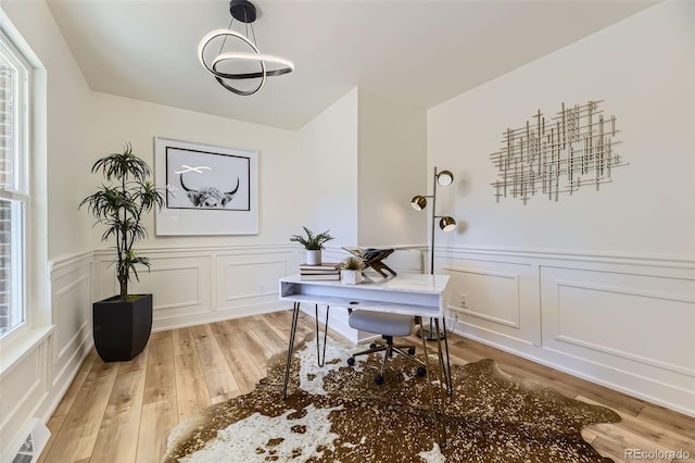 home office featuring a wainscoted wall, visible vents, a decorative wall, and light wood finished floors