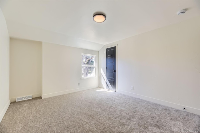 spare room with lofted ceiling, carpet, visible vents, and baseboards