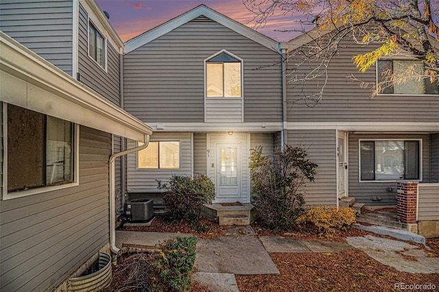 back house at dusk featuring central AC