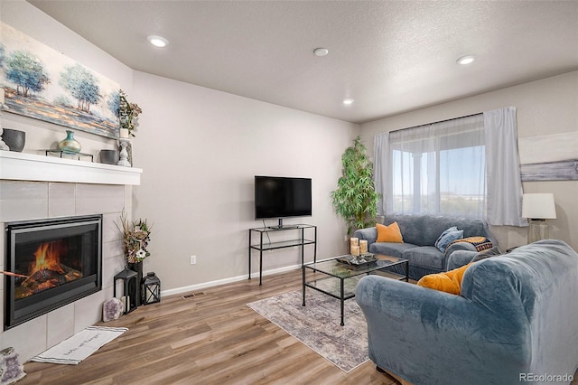 living room featuring a textured ceiling, wood-type flooring, and a fireplace