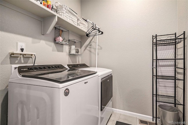 clothes washing area with light tile patterned flooring and washer and dryer