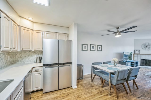 3240 Iris Ave Unit G409, Boulder, CO 80301 - kitchen featuring appliances with stainless steel finishes, light countertops, ceiling fan, light wood-style flooring, and decorative backsplash