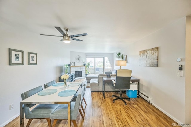3240 Iris Ave Unit G409, Boulder, CO 80301 - dining room with wood finished floors, a tiled fireplace, a baseboard radiator, a ceiling fan, and baseboards