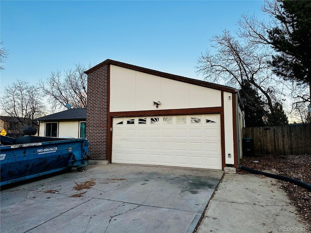 garage with concrete driveway and fence