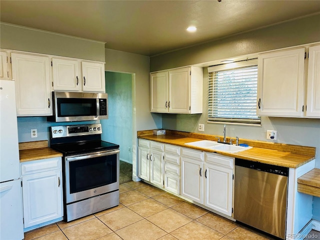 kitchen with light tile patterned floors, stainless steel appliances, a sink, and white cabinets