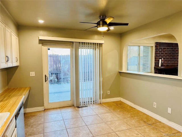 entryway with light tile patterned floors, plenty of natural light, a ceiling fan, and baseboards