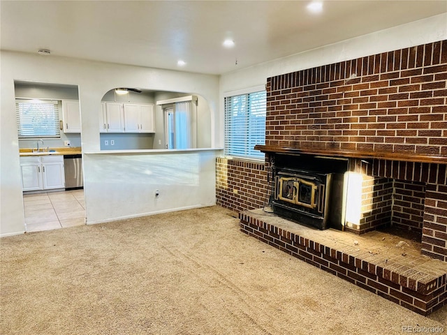 kitchen with light carpet, light tile patterned floors, white cabinets, stainless steel dishwasher, and a sink