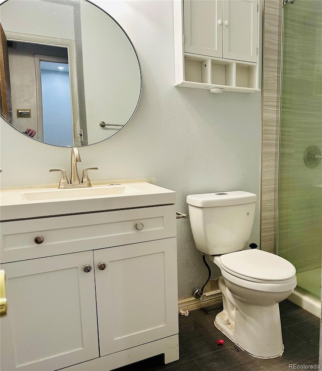 bathroom featuring toilet, a stall shower, wood finished floors, and vanity