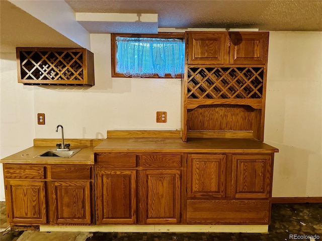 bar featuring a textured ceiling, wet bar, and a sink