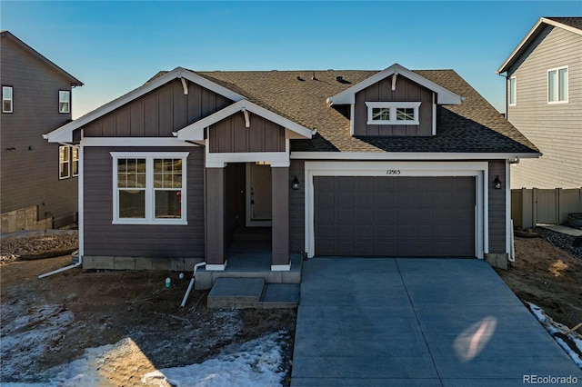 view of front of home with roof with shingles, board and batten siding, fence, a garage, and driveway