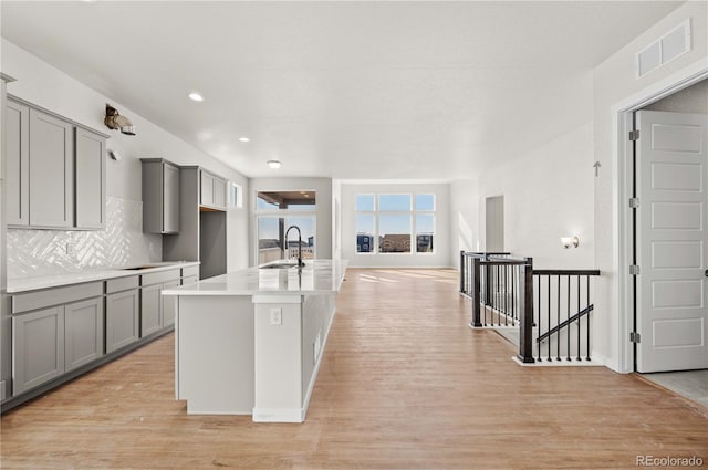 kitchen with light wood-style floors, visible vents, gray cabinets, and a sink