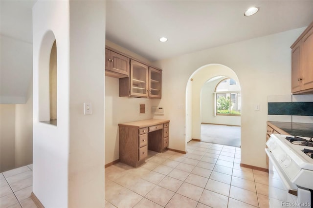 174 Luxury Ln, Colorado Springs, CO 80921 - kitchen featuring arched walkways, gas range gas stove, light tile patterned floors, recessed lighting, and glass insert cabinets