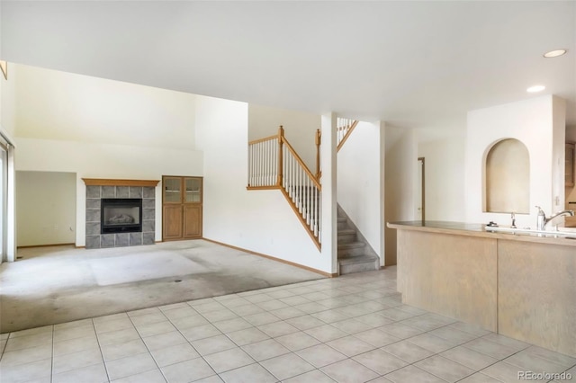 174 Luxury Ln, Colorado Springs, CO 80921 - unfurnished living room featuring a tiled fireplace, stairs, recessed lighting, and light colored carpet