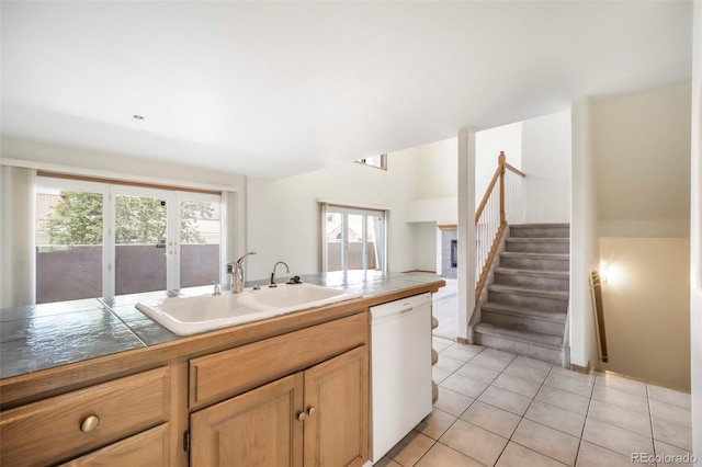 174 Luxury Ln, Colorado Springs, CO 80921 - kitchen with white dishwasher, light tile patterned flooring, light brown cabinets, and tile countertops