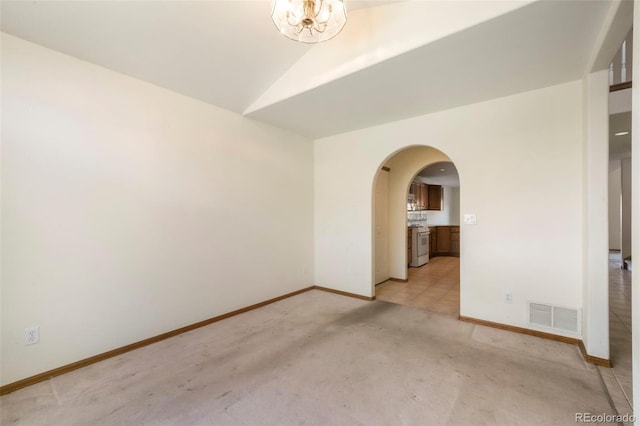 174 Luxury Ln, Colorado Springs, CO 80921 - empty room featuring arched walkways, light carpet, and vaulted ceiling