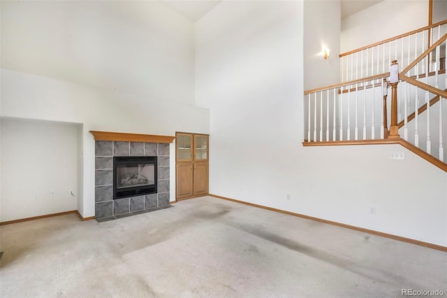 174 Luxury Ln, Colorado Springs, CO 80921 - unfurnished living room featuring carpet flooring, stairs, a tile fireplace, and a high ceiling