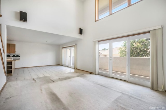 174 Luxury Ln, Colorado Springs, CO 80921 - unfurnished living room featuring carpet floors, a high ceiling, and tile patterned floors